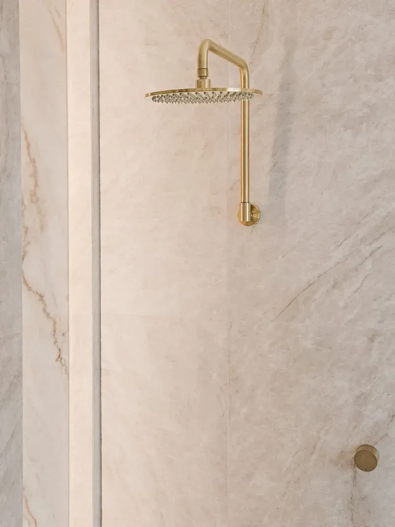 Full-height stone shower cladding with brass fixtures